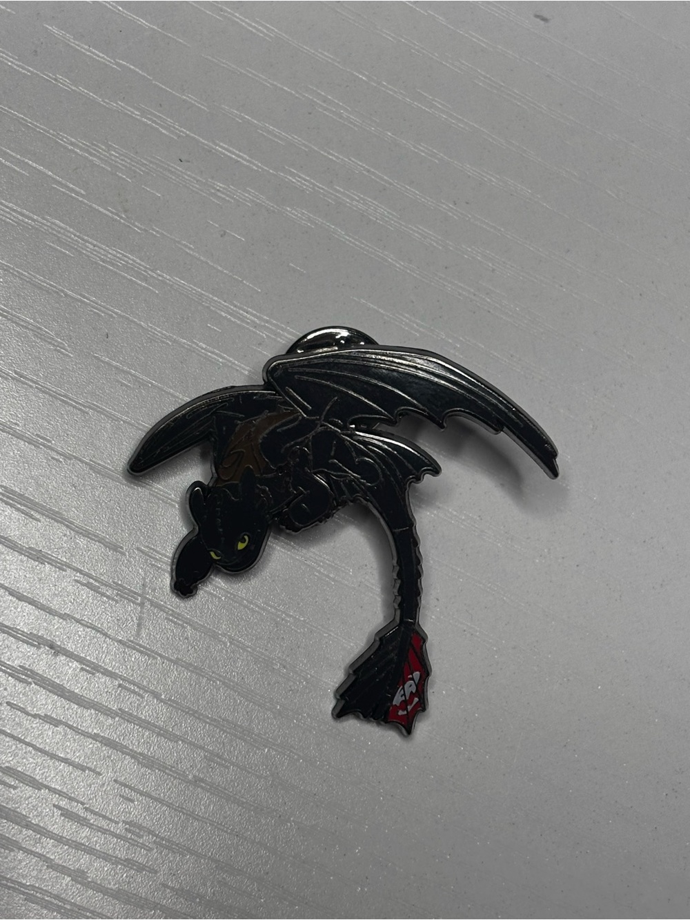 Toothless enamel pin